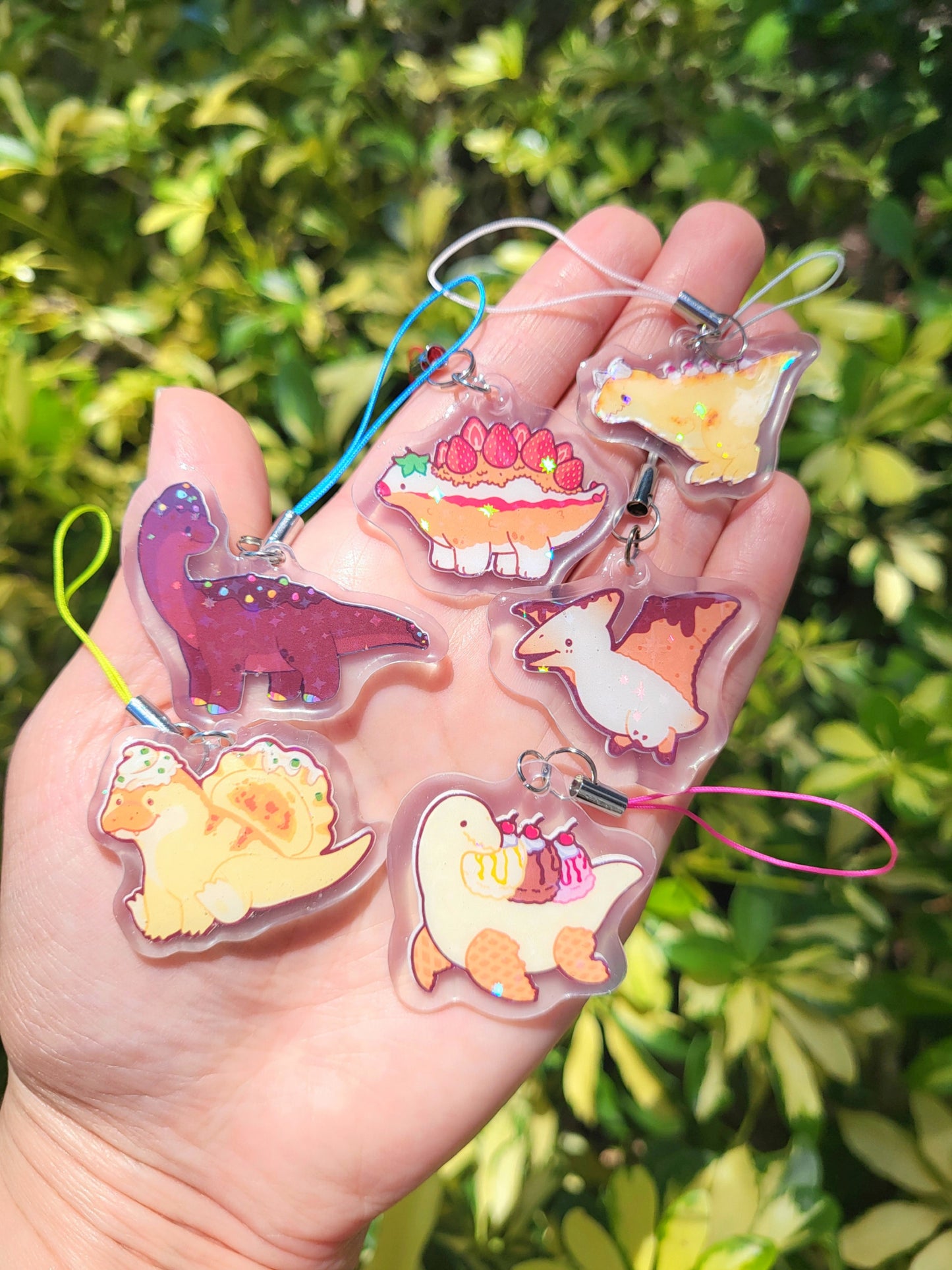 Six handmade phone charms by OsoCuteClub featuring their Mesozoic Bites designs. These cute characters are food-inspired dinosaurs.