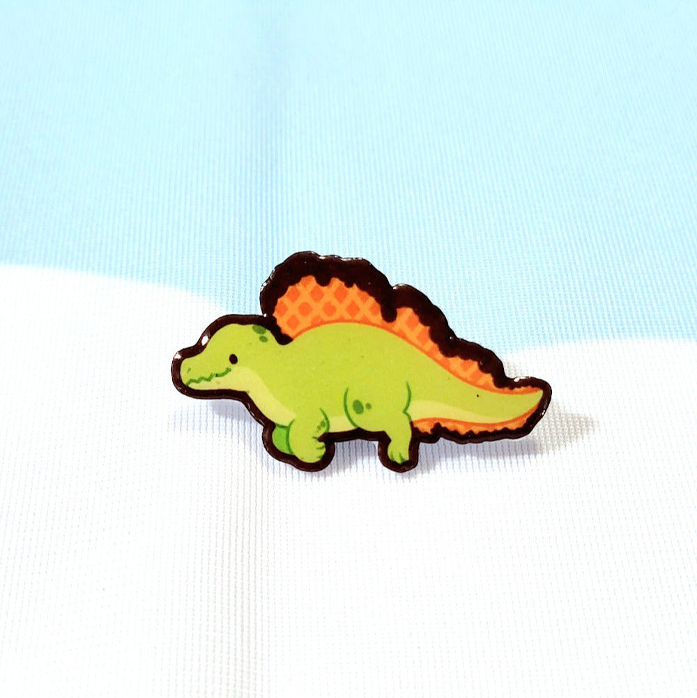 A plastic pin of a green spinosaurus with a chocolate-dipped waffle pattern on the sail along its spine